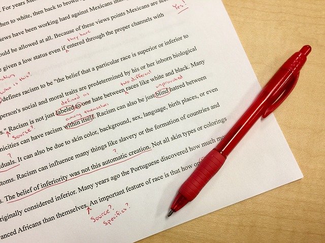 a paragraph was proofread using the red pen beside the paper on the desk